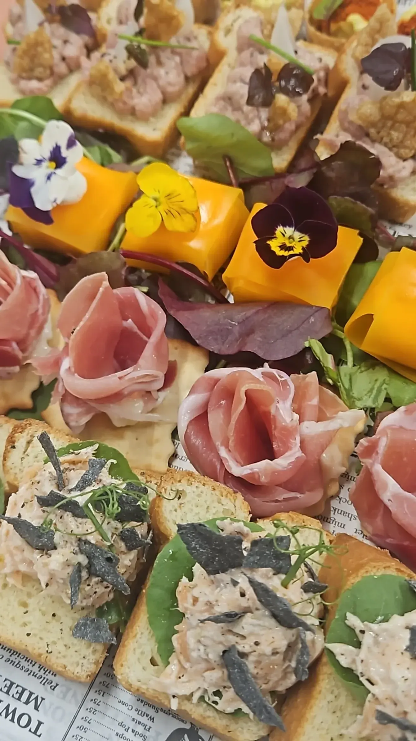 Schaal met luxe borrelhapjes: ham, vis en gemarineerde groenten op brioche