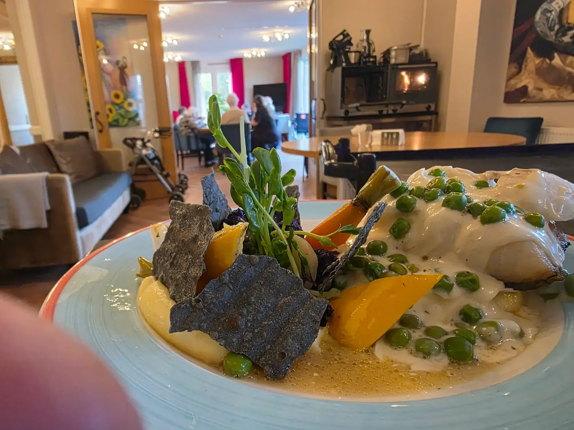 Bord met vis, doperwten en aardappel, uitgeserveerd in de woonkamer van een zorglocatie