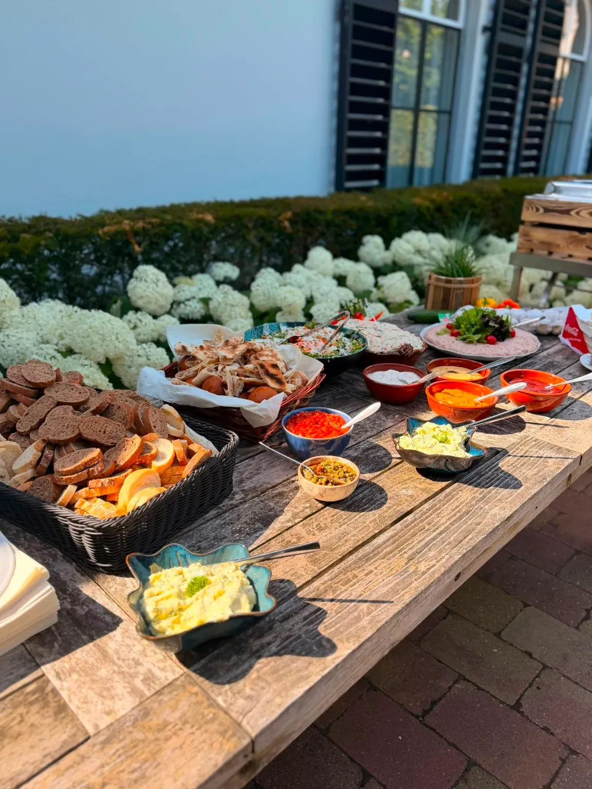 Ruime buffettafel met vlees, sauzen en bijgerechten, hortensia's op de achtergrond