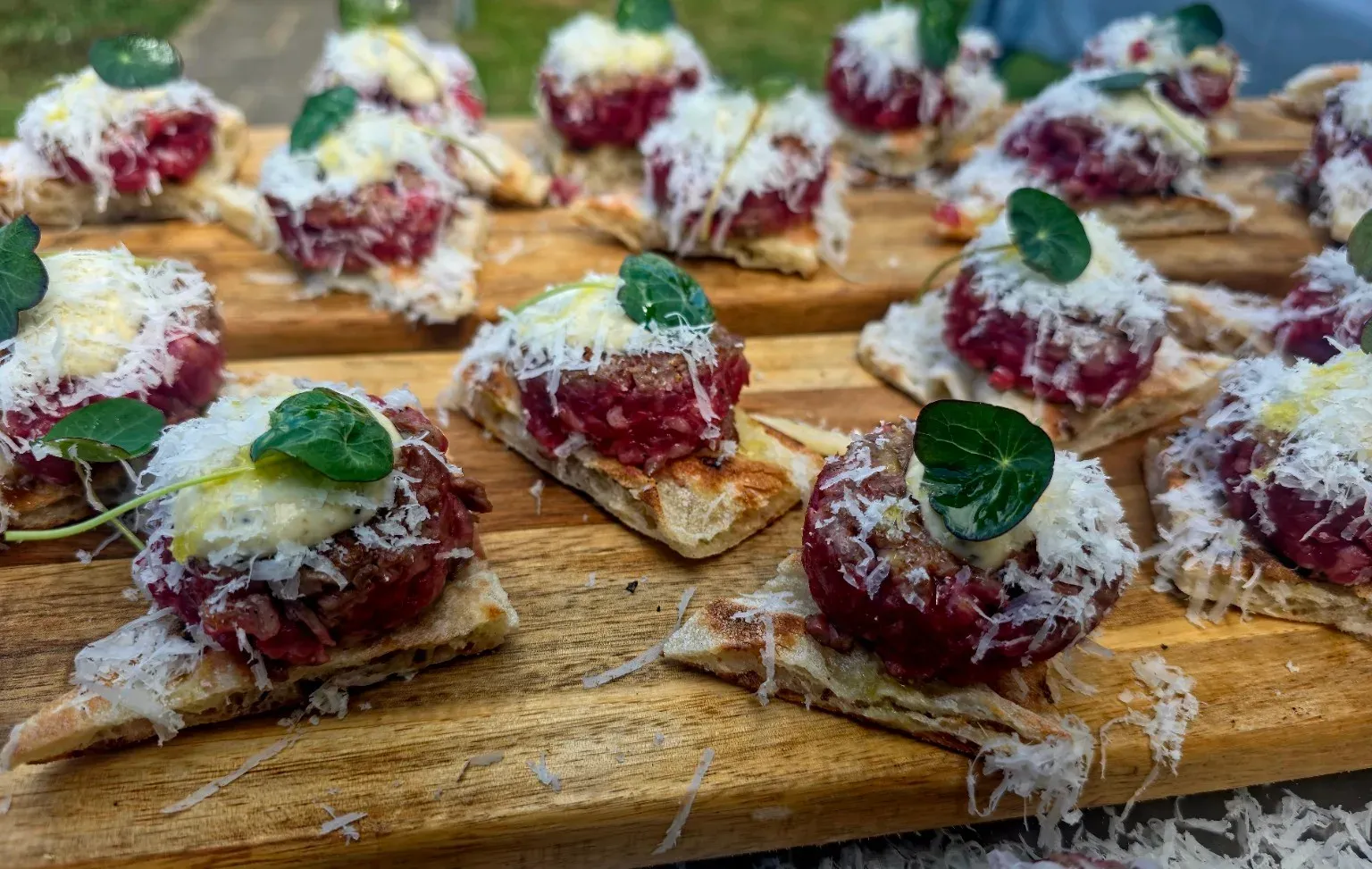 Bavette- en bietenbruschetta met Parmigiano en oostindische kers op een houten plank