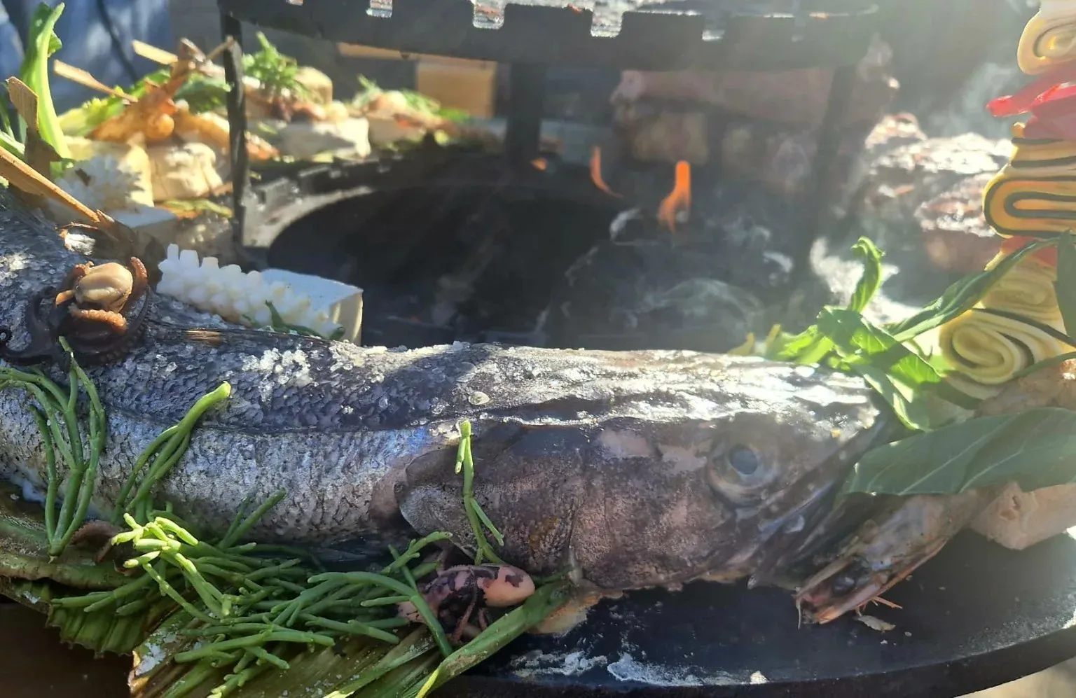Hele vis van de plancha met sperziebonen en kruiden, vuur op de achtergrond